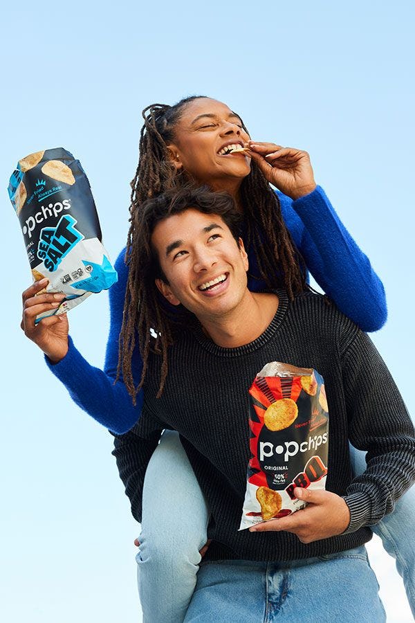 A woman and man holding bags of Popchips