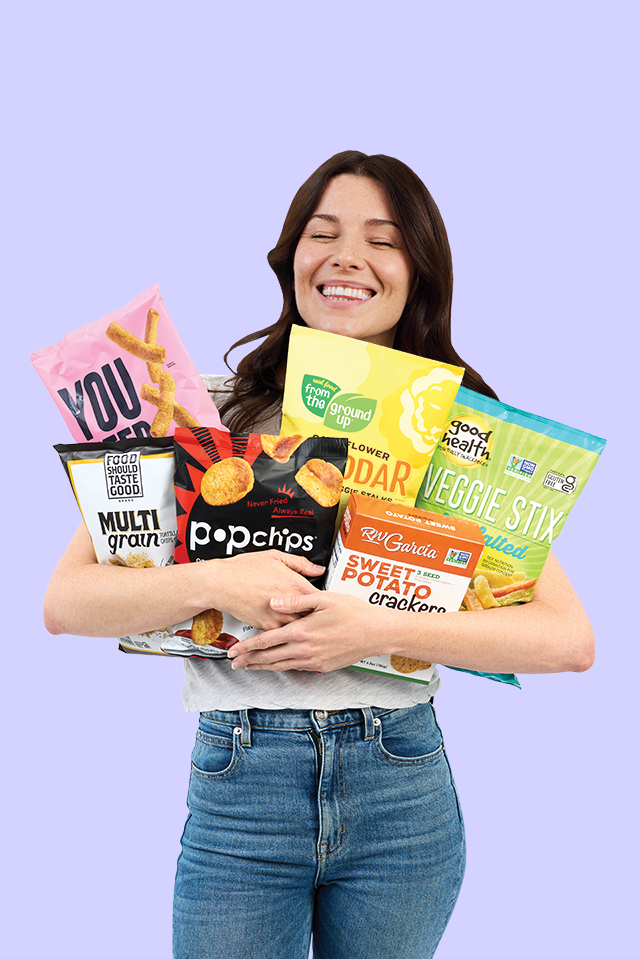 A woman holding 6 packages of snacks