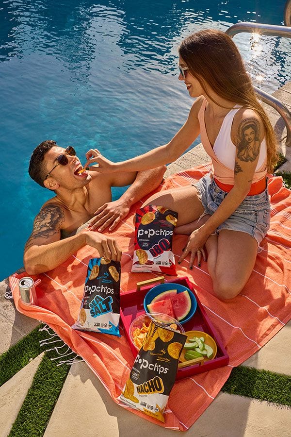 A man and woman eating Popchips in a pool
