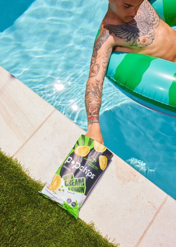 Person in a pool reaching for a bag of Popchips