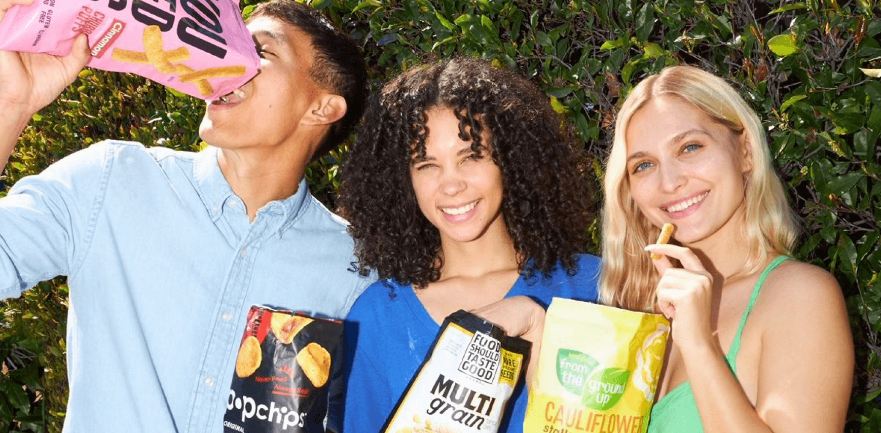 Three people holding various bags of chips and smiling at the camera.