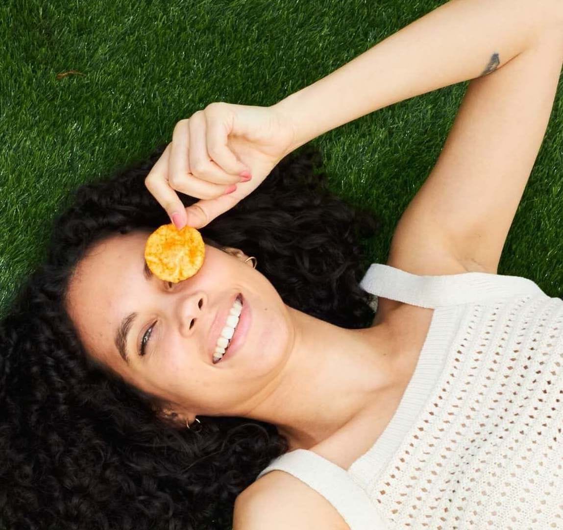 Woman holding a pop chip above her eye.